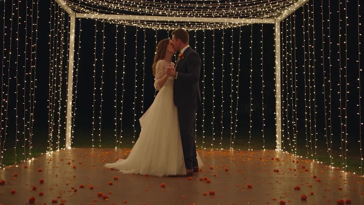A couple sharing their first dance under a canopy of fairy lights